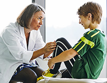 doctor looking at kids knee 