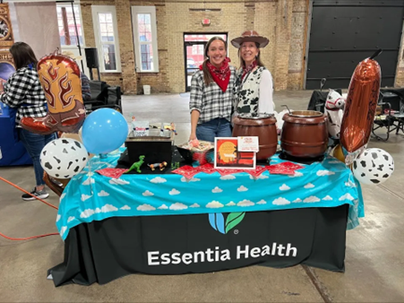 two females standing behind a table with items on it.